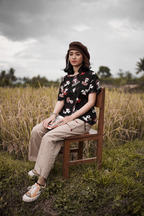 A Pretty Girl with a Hat Sitting on a Wooden Chair 