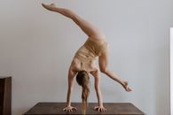 一名女子穿着运动服，在极简主义背景的室内倒立