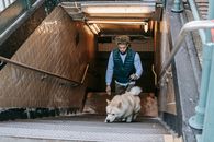 Black man with dog walking upstairs in subway