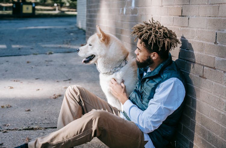 Black Man Sitting With Dog On Street