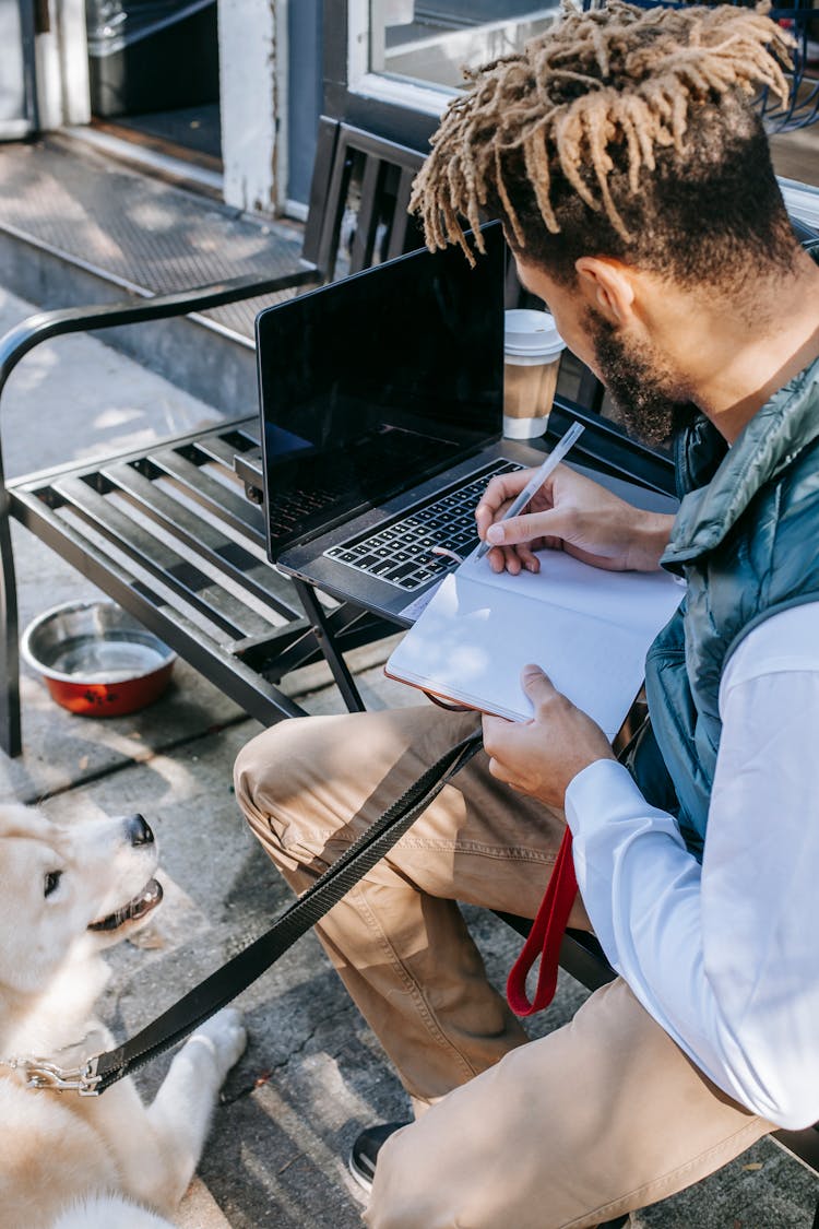 Black Man With Cute Dog Taking Notes In Notebook