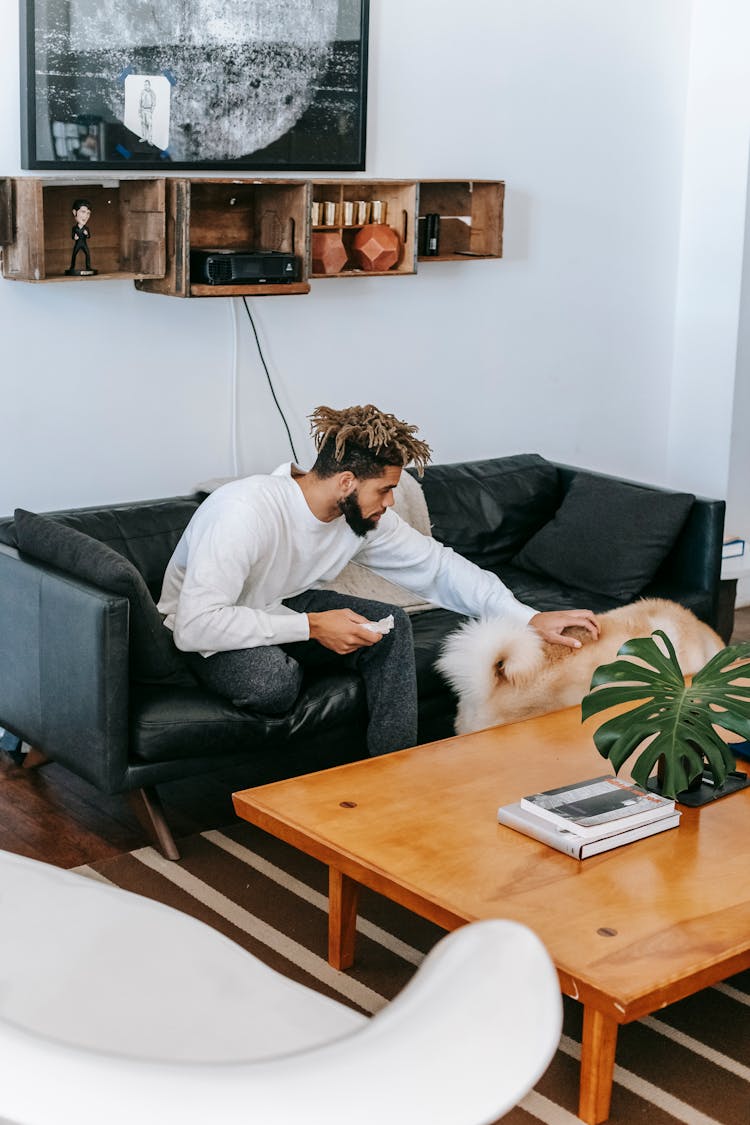 Black Man Sitting On Couch Near Dog