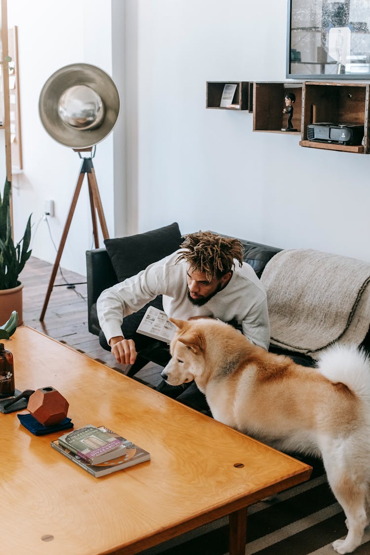 Curious Black Man Sitting On Couch With Dog