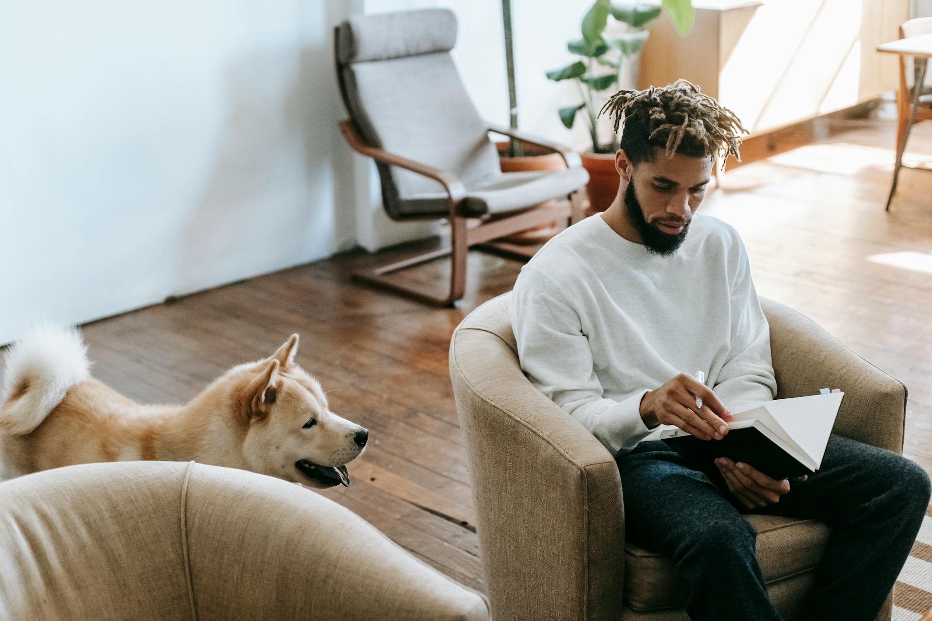 Svart man med anteckningsbok nära hund