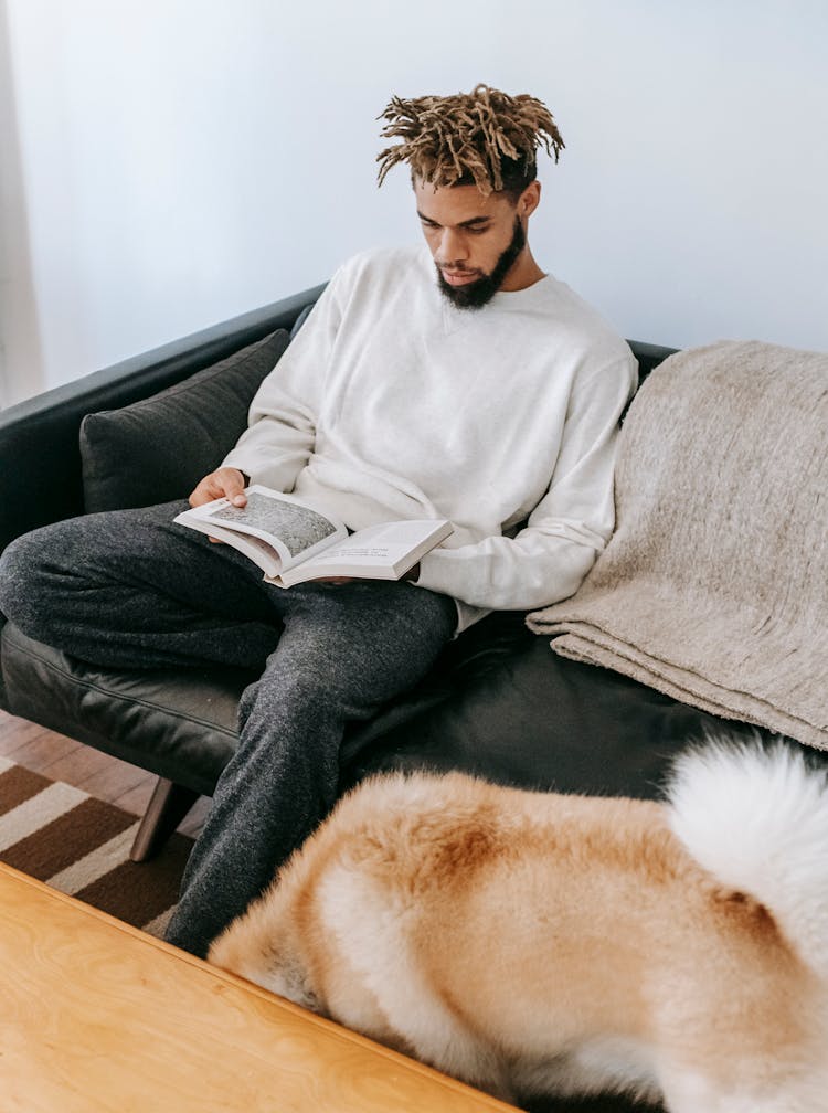 Focused Black Man With Book Near Dog