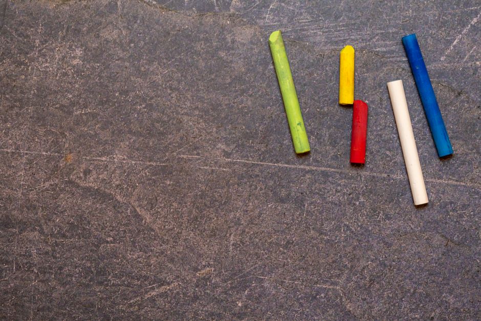 Top view set of multicolored round chalks for drawing scattered on dark shabby surface with painted lines in modern studio