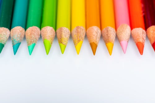 Free From above set of multicolored wooden pencils with sharp tips arranged in neat row placed on white surface in light room Stock Photo