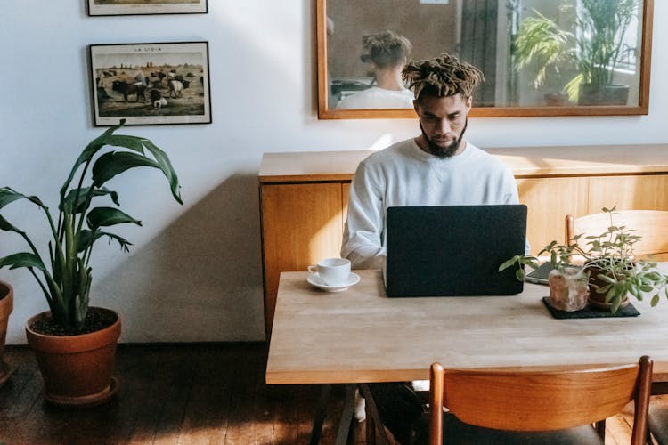 Focused Black Man Browsing Laptop At Home