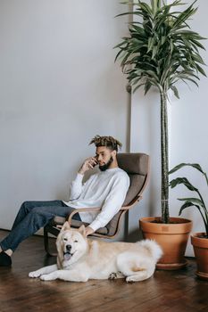 在现代客厅里，年轻人带着秋田犬，一边打电话聊天一边放松