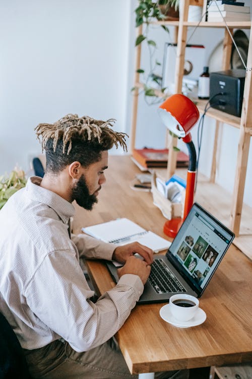 Free African American man freelancer working on netbook in light room Stock Photo