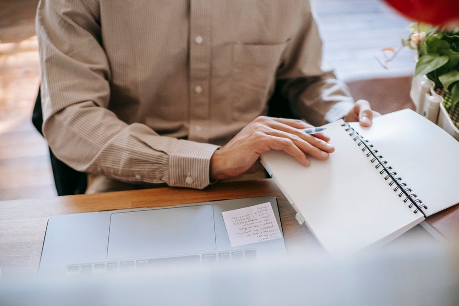 person writing notes workflow planning desk