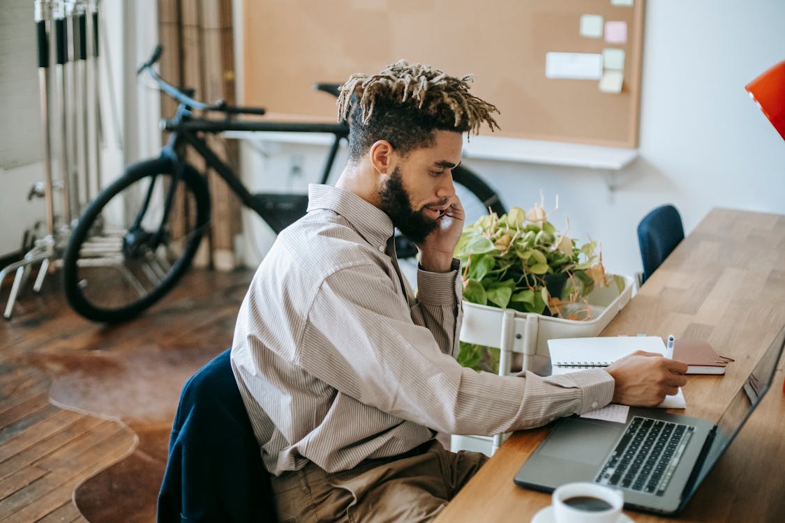 Free Black Man Working Remotely On Laptop In Workspace Stock Photo