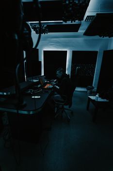 A music producer sits at a workstation in a soundproof studio, focused on creating music.
