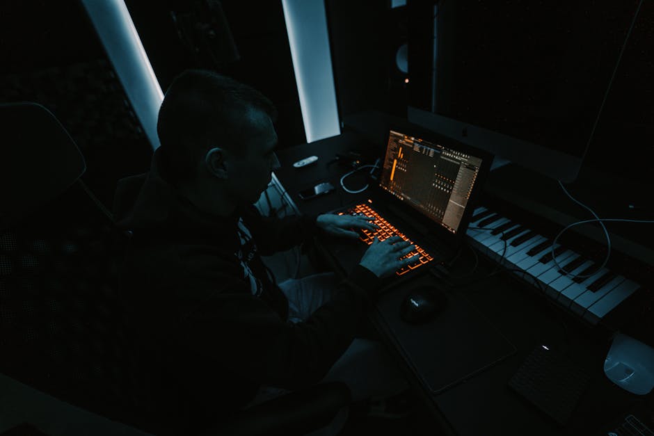 ElevenLabs vs Murf AI: Education Voice Quality (2025) Music producer focused on composing tracks in a dimly lit studio with laptop and keyboard.