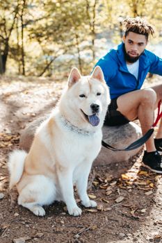 秋日阳光明媚，一名男子带着秋田犬坐在户外，尽显友谊与宁静