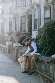 年轻人在城市街道上与秋田犬亲密相处，展现了休闲的都市生活方式