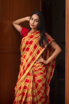 Portrait of a woman in a colorful sari posing indoors, exuding grace and tradition.