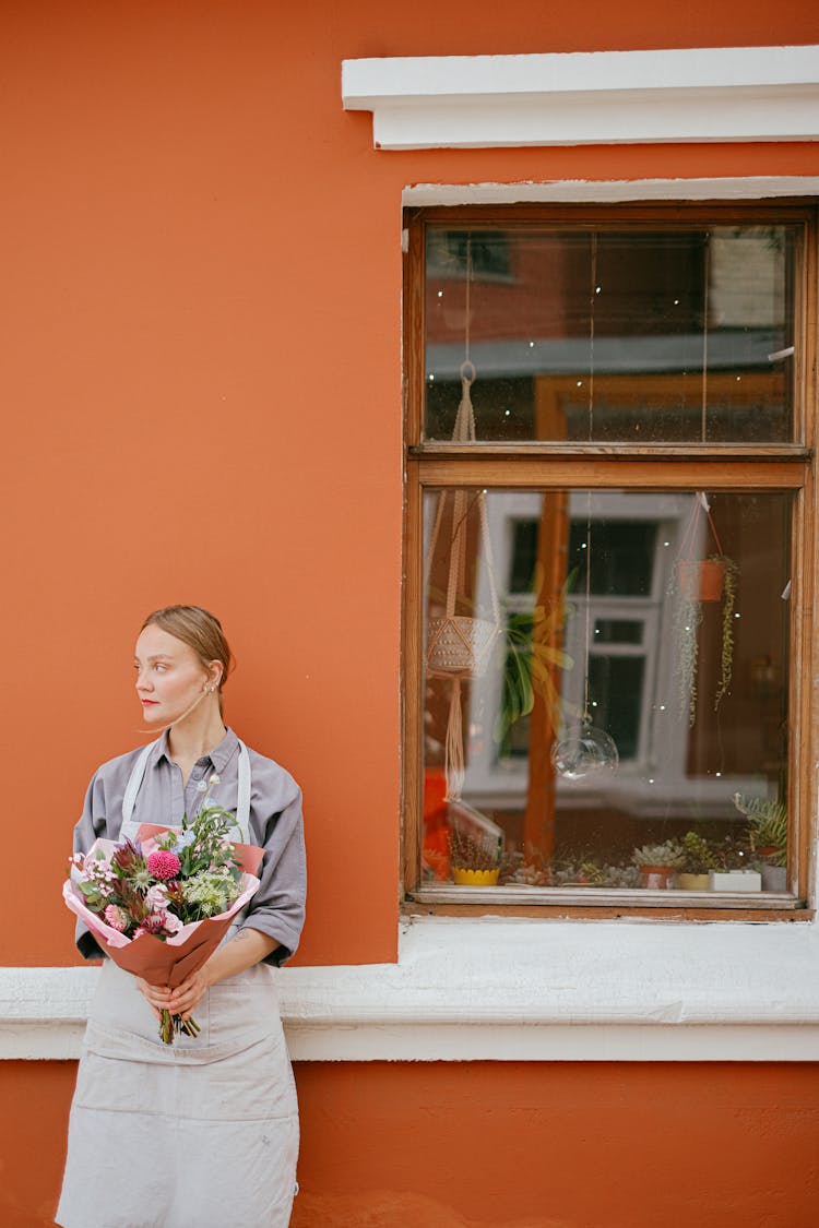 Serious Florist With Flowers At Building