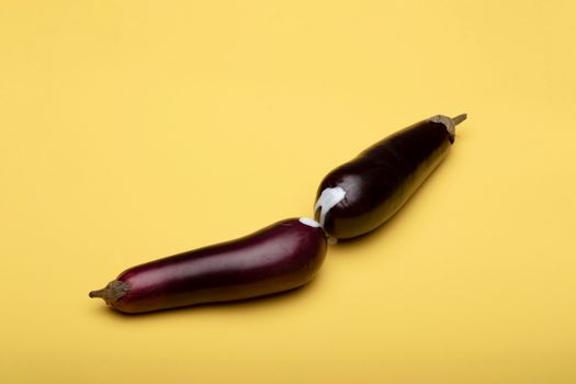 A conceptual image featuring two eggplants against a yellow backdrop, symbolizing creativity.