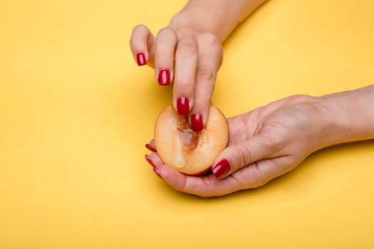Creative conceptual image featuring hands holding and touching a peach on a vibrant yellow background.