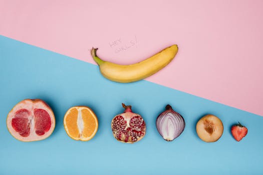 Artistic arrangement of fruits and vegetables on a split pastel background creating a conceptual visual.