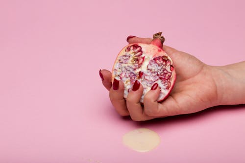 A Person Holding Sliced Pomegranate Fruit