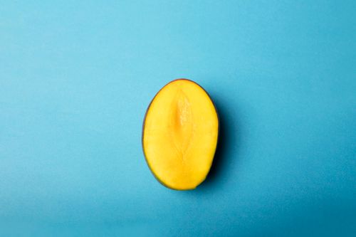 Free A vibrant half mango against a blue backdrop, providing rich color contrast. Stock Photo