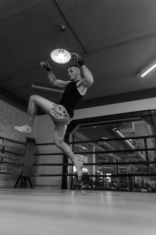 Free Black and white photo of an athlete in midair performing a jumping kick in a boxing ring. Stock Photo