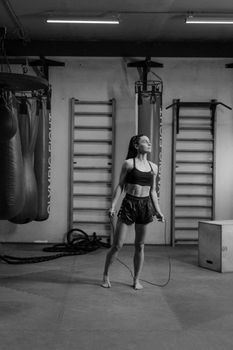 A woman in activewear using a jump rope in a gym setting.