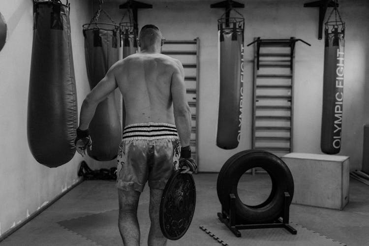 Shirtless Man Carrying A Weight Plate