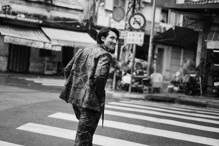 Happy Young Ethnic Man Walking On Zebra Crossing In Old Town