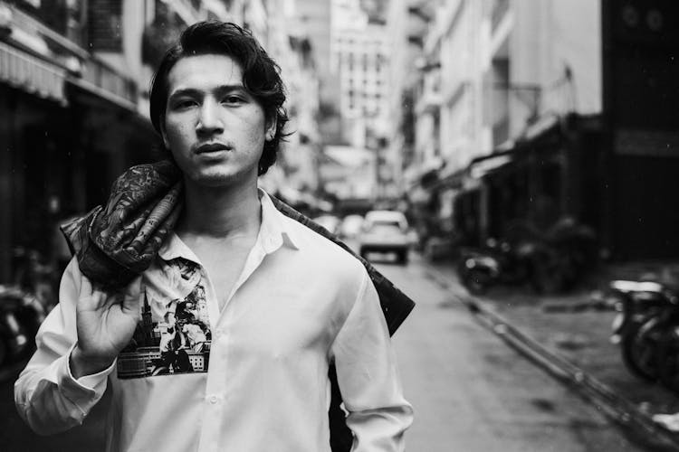 Confident Young Ethnic Man With Blazer Over Shoulder Standing On Street