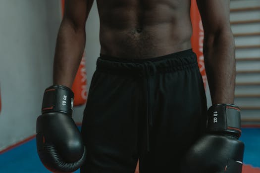 Focused shot of a shirtless boxer wearing gloves during practice session.