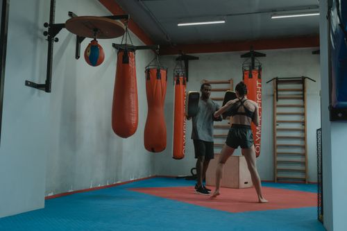 Free Boxer and trainer in an indoor gym practicing with focus mitts and boxing gloves. Stock Photo