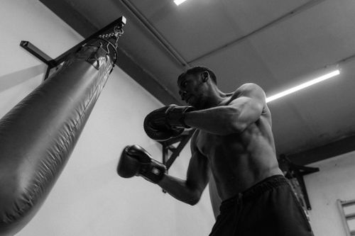 Free A muscular boxer training intensely with a punching bag in a gym setting. Stock Photo
