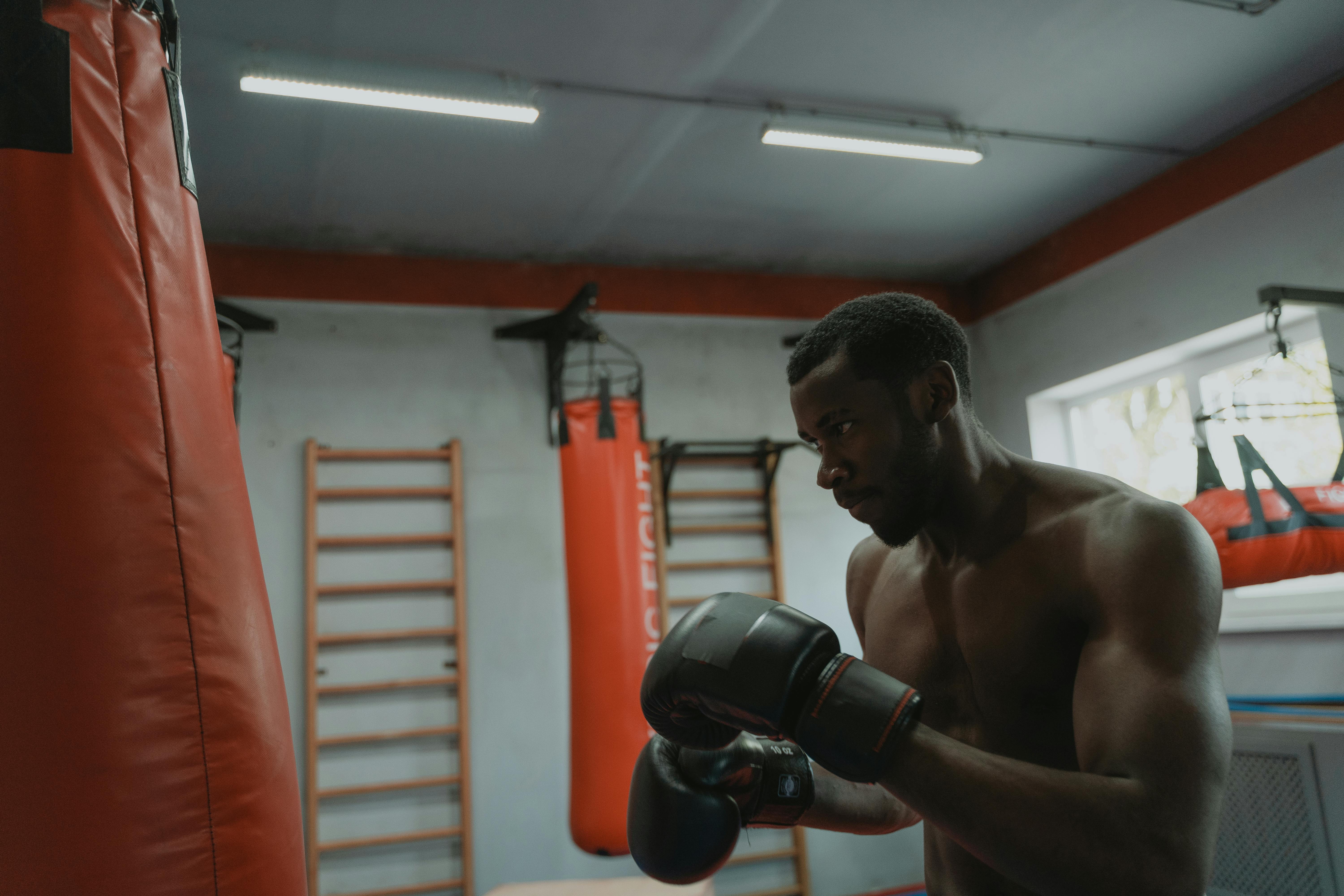 Young woman standing in the corner of a boxing ring preparing to practice  kickboxing or boxing Stock Photo by luismanuelm