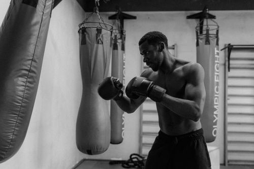 Free Dynamic black and white shot of a muscular boxer training in a gym, showcasing strength and focus. Stock Photo