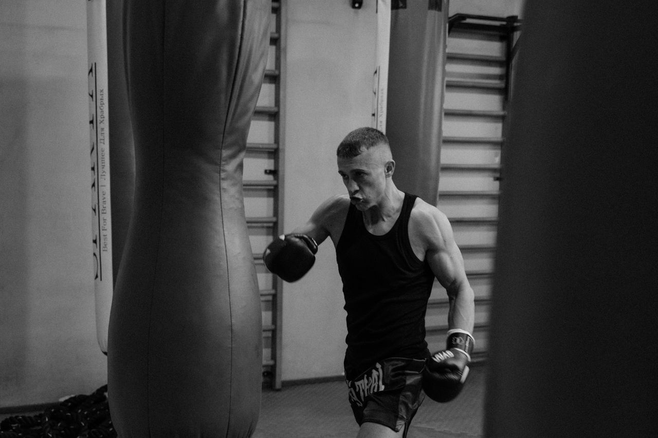 black and white photo of a muscular male boxer training with punching