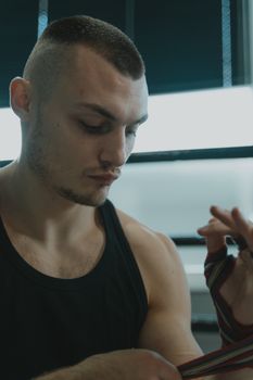 一名肌肉发达的男子在健身房里用带子包裹双手的特写