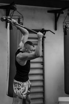 A muscular man performing a powerful workout using a sledgehammer in a gym.