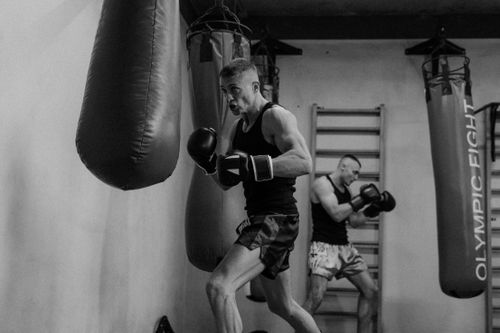 Free Athletes practicing boxing in a gym, showcasing dynamic movement and focus in black-and-white. Stock Photo