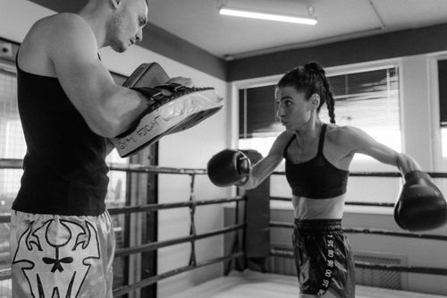 Free Focused boxer sparring with a trainer in a monochrome gym setting. Stock Photo