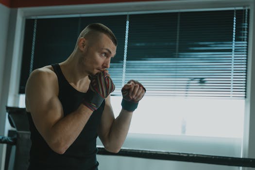 A muscular man practicing boxing techniques inside a gym, showcasing strength and discipline.