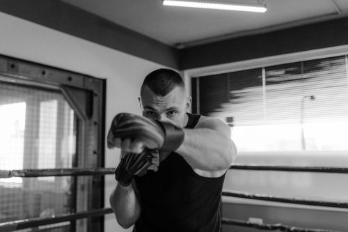 Free A muscular man shadow boxing energetically inside a gym, captured in dramatic black and white. Stock Photo