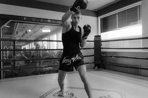Free Black and white photo of a boxer practicing punches in an indoor gym ring. Stock Photo