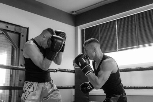 Free Intense black and white shot of two men sparring in a boxing ring. Captures the essence of combat sports. Stock Photo