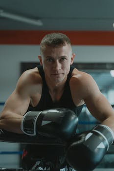 Focused young man in boxing gloves ready for training indoors.