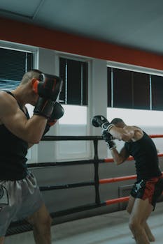 Two men engaged in a dynamic boxing sparring match inside a gym.