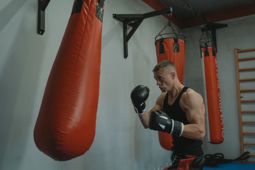 Free Adult male training with boxing gloves in a gym punching bag area. Fitness and determination. Stock Photo
