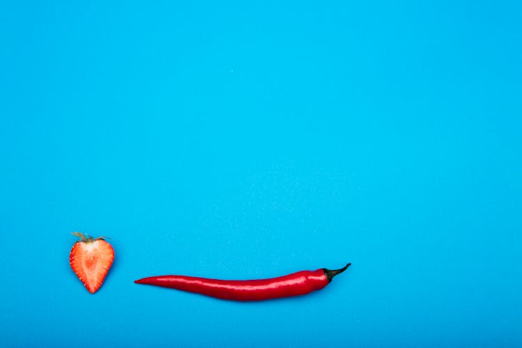 Half Of A Strawberry Beside A Red Pepper 